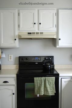 a black stove top oven sitting inside of a kitchen next to white cabinets and cupboards