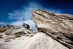 a large rock sitting on top of a sandy beach next to a blue cloudy sky