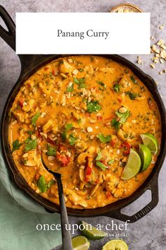 a pan filled with chicken curry and garnished with cilantro, limes,