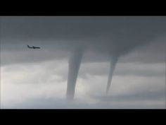 an airplane flying in front of two tornado clouds