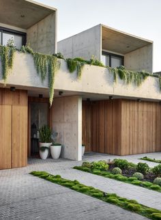 an exterior view of a modern house with plants growing on the balconies and wooden doors