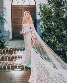 a woman in a wedding dress is standing on the steps with her veil blowing in the wind