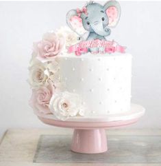 a white cake with pink flowers and an elephant topper