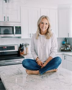 a woman sitting on top of a kitchen counter