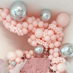 an overhead view of balloons and other decorations in pink, silver and white colors on a wall