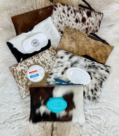 several different animal print clutches and purses on a white fur surface with a blue tag