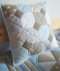 a close up of a pillow on a bed with blue and white quilting,