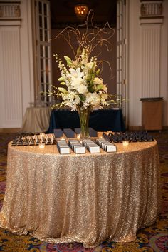 the table is covered with gold sequins and white flowers