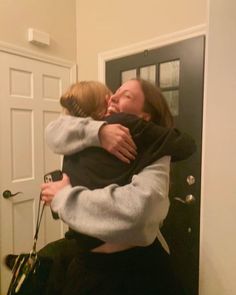 two women hugging each other in front of a door