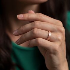 a close up of a person wearing a wedding band and holding their hand in front of her face