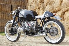 a black and silver motorcycle parked in front of some bales of hay on the ground