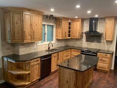 a large kitchen with wooden cabinets and black counter tops, an island in the middle