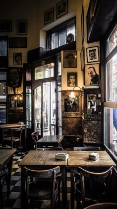 an empty restaurant with tables and chairs in front of large windows, framed pictures on the wall