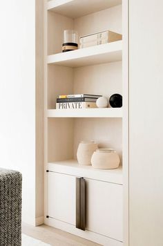 a white book shelf with books and vases on it