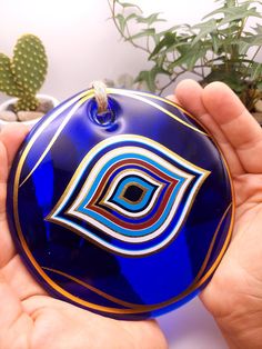 a hand holding a blue glass ornament with a design on it