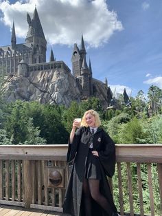 a woman standing on a wooden deck in front of hog potter's castle with her hair blowing in the wind