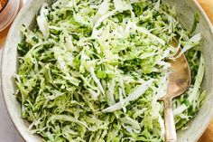 a bowl filled with shredded cabbage next to a spoon