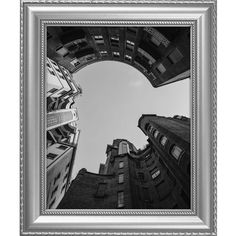 the view from below looking up at tall buildings in black and white with an oval silver frame