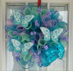 a wreath made out of mesh and paper butterflies on a window sill with red ribbon