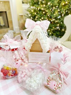 a table topped with lots of candy and candies next to a small house shaped like a gingerbread