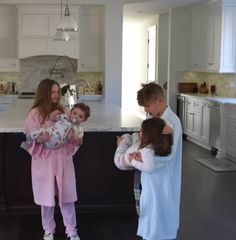 three children and an adult standing in a kitchen