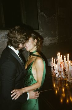 a man and woman standing next to each other in front of candles