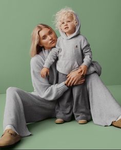 a woman sitting on the ground with a child in her lap, both wearing pajamas