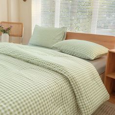 a bed with green and white checkered bedspread in front of a window