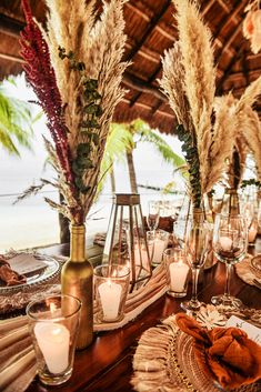 the table is set with candles, plates and vases filled with pamodia