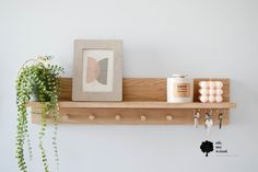 a wooden shelf with two candles and a potted plant on it next to a framed photograph