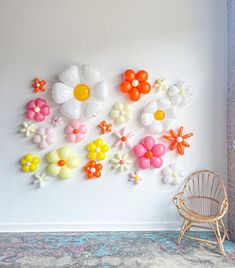 there is a wall decoration made out of balloons and flowers on the wall next to a chair