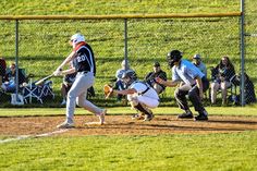 a baseball player swinging a bat on top of a field with people sitting in the bleachers behind him