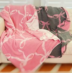 a pink and gray blanket sitting on top of a white couch