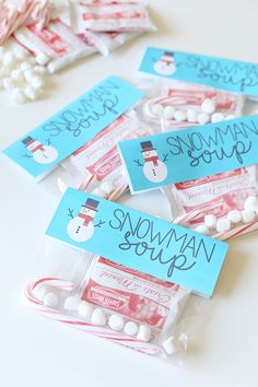 snowman soup packets with candy in them sitting on a table next to marshmallows