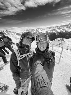 black and white photograph of skiers taking selfie on ski slope with mountains in background