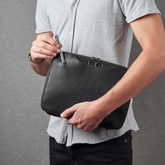 a man is holding a black leather bag