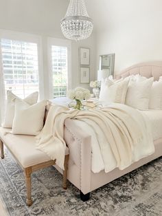 a bedroom with a bed, chandelier and pillows on top of the bed