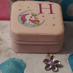 a pink suitcase sitting on top of a table next to a small metal flower brooch