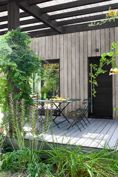 an outdoor patio with table and chairs surrounded by greenery on the decking area