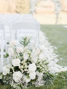 a bouquet of white flowers sitting on top of a grass covered field next to chairs