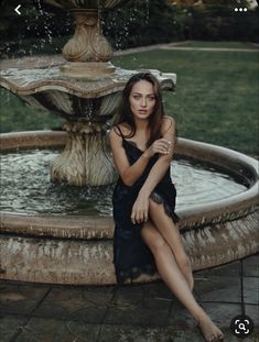 a woman sitting in front of a fountain