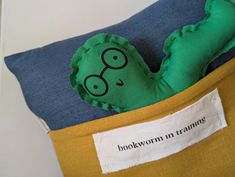 a green stuffed animal in a yellow and blue pillow