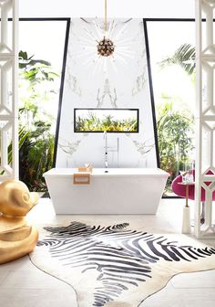 a white bath tub sitting under a window next to a rug on top of a floor