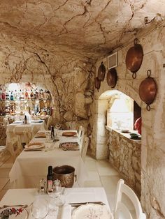 a dining area with tables and chairs in an old stone walled restaurant, filled with wine bottles