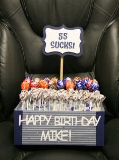 a happy birthday sign sitting on top of a chair next to chocolate covered lollipops