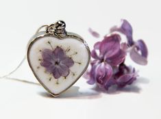 "Lilac Cremation Jewelry, Ashes Jewelry, Custom Urn Jewelry, Urn Necklace, Pet Ashes Jewelry, Memorial Jewelry, Ashes Necklace This cremation urn necklace is decorated with real Queen Annes Lace and a real pressed lilac. The flowers are safely covered in jewelry-grade resin. You choose the black or white background. The heart is 1.1 inches wide and tall and is about 1/4 inch thick. It comes on a sterling silver plated chain, which is 18 inches long. I also have 20 inch chains. If you want the lo Lilac Jewelry, Urn Necklaces For Ashes, Pet Ashes Jewelry, Memorial Jewelry Ashes, Custom Urns, Ashes Necklace, Urn Pendant, Urn Jewelry, Urn Necklace