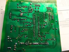 an electronic circuit board with many small screws on the top and bottom, sitting on a piece of paper