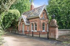 an old brick building with a black fence around it and trees surrounding the area behind it