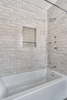 a white bath tub sitting inside of a bathroom next to a shower head and hand rail