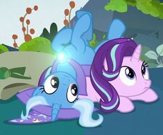 two little ponys laying on the ground with their eyes open and one has its head down